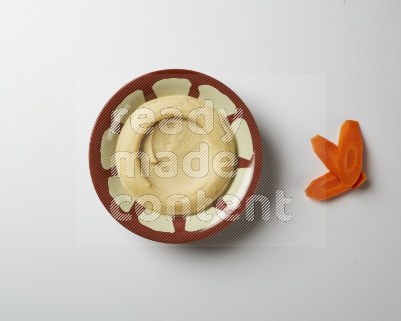 Plain hummus in a traditional plate on a white background