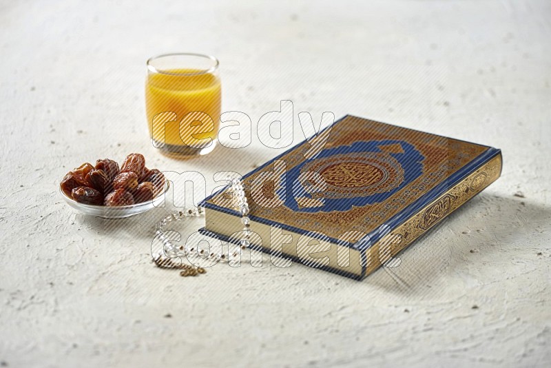 Quran with dates, prayer beads and different drinks on textured white background