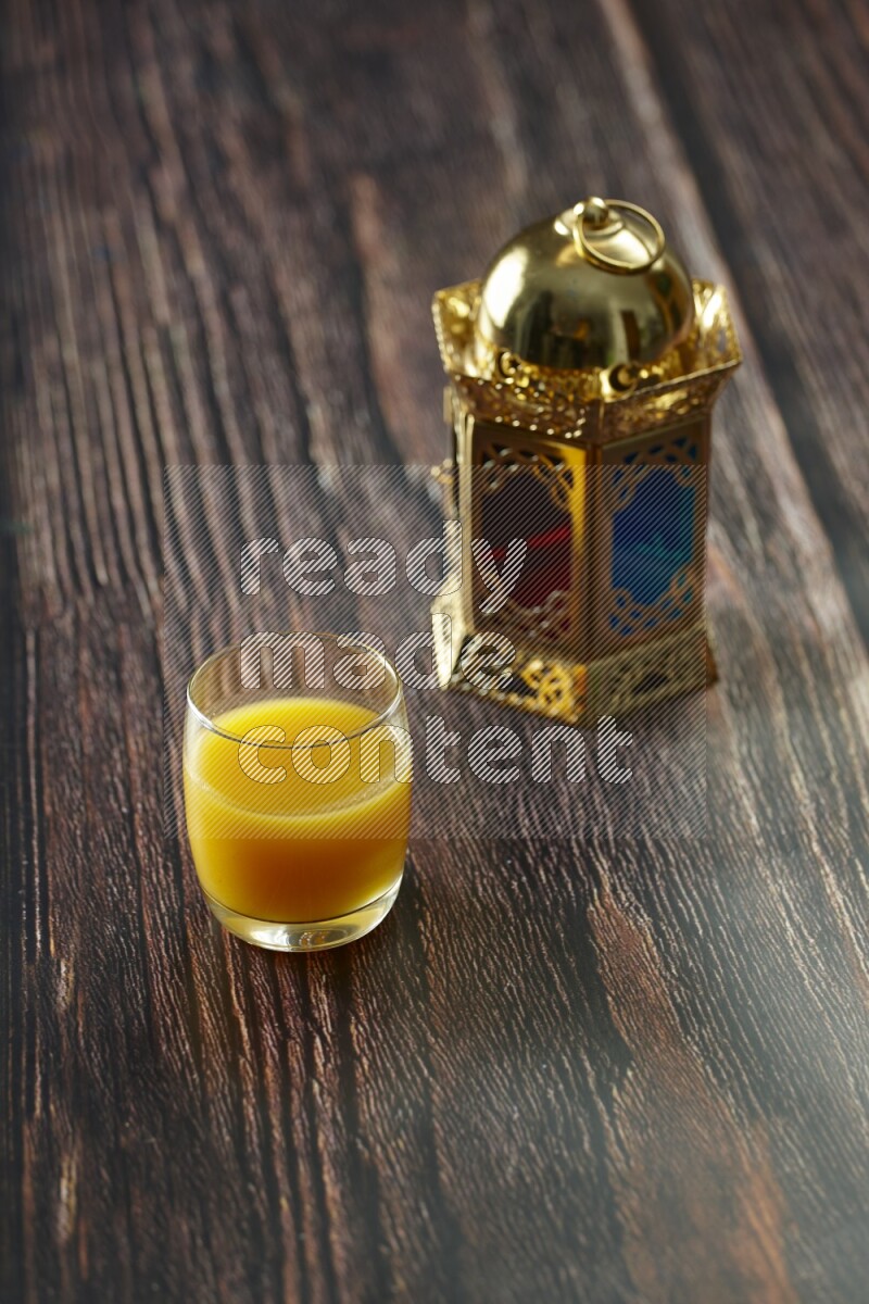 A golden lantern with different drinks, dates, nuts, prayer beads and quran on brown wooden background