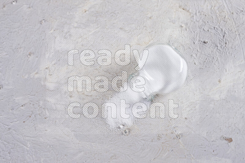 A glass jar full of fine table salt on white background