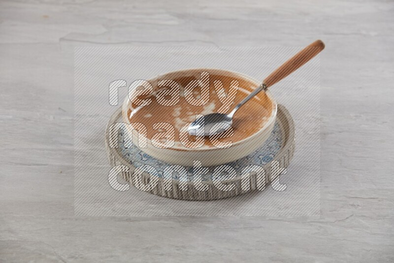 multi color pottery round dish on top of multi color round ceramic plate and spoon, on grey textured countertop