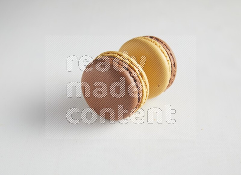 45º Shot of two Yellow and Brown Chai Latte macarons on white background