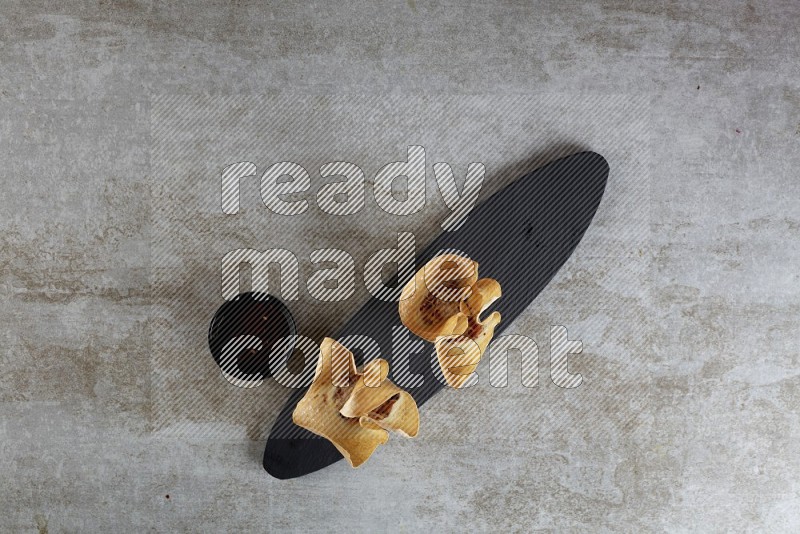 wonton cups with soy sauce ramkin on oval slate on grey textured counter top