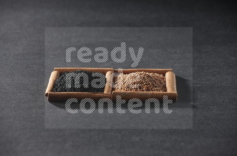 مربعان من أعواد القرفة ممتلئان بحبوب الخردل وحبة البركة السوداء علي خلفية سوداء