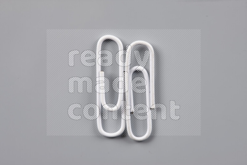 White paper clips isolated on a grey background
