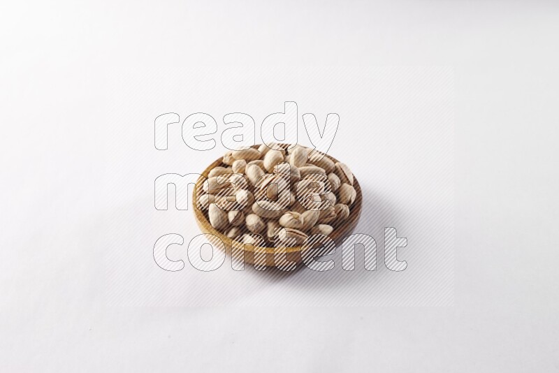 Pistachios in a wooden bowl on white background