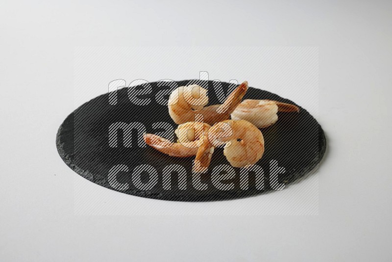 four grilled shrimp  on a black slate direct  on a white back ground