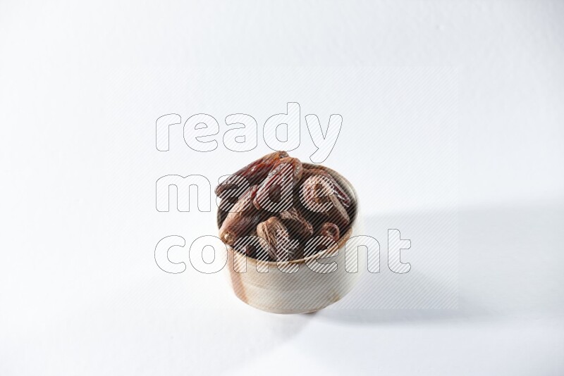 A beige ceramic bowl full of dried dates on a white background in different angles