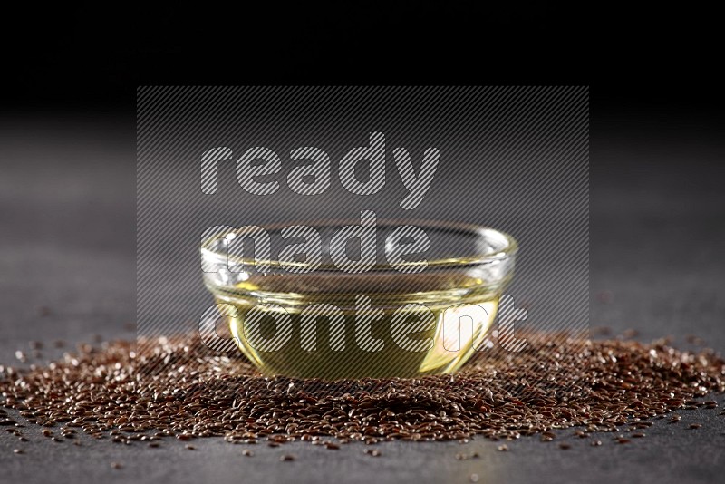 A glass bowl full of flax oil surrounded by the seeds on a black flooring in different angles