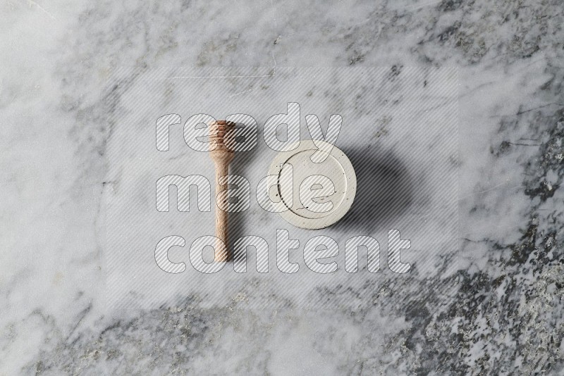 White Pottery Bowl with wooden honey handle on the side on grey marble flooring, Top view