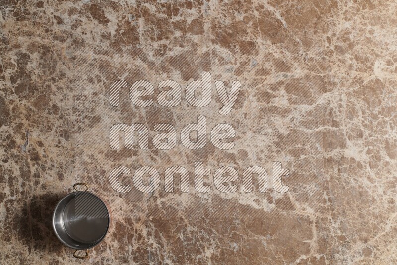 A small copper pot on beige marble background