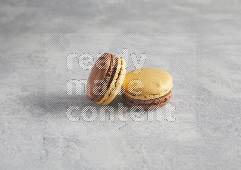 45º Shot of two Yellow and Brown Chai Latte macarons r on white  marble background