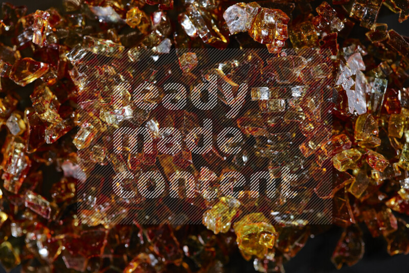 Transparent orange fragments of glass scattered on a black background