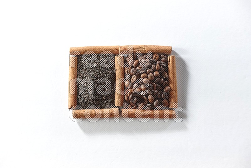 مربعان من أعواد القرفة ممتلئان بحبوب القهوة والشاي الأسود علي خلفية بيضاء