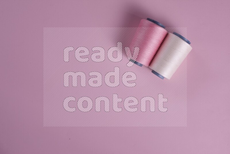 A white and pink collection of sewing and tailoring tools arranged on a pink background