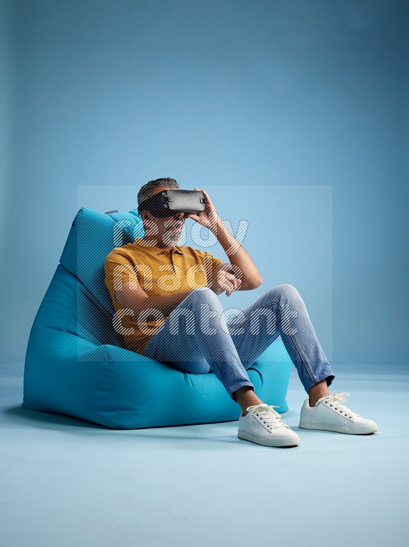 A man sitting on a blue beanbag and gaming with VR