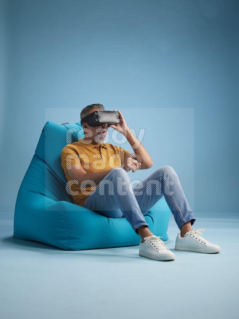 A man sitting on a blue beanbag and gaming with VR