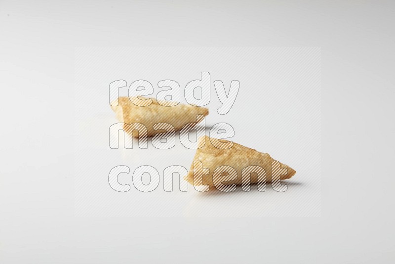 Two fried sambosas on a white background