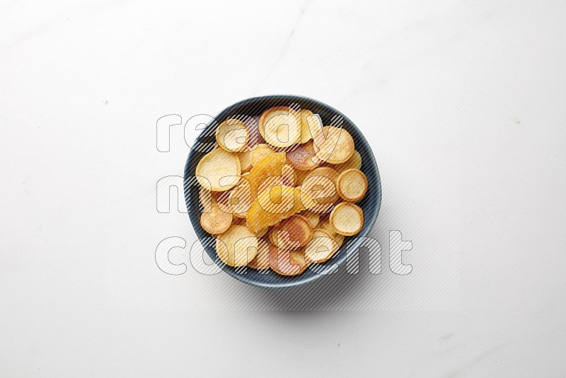 Top-view shot of orange candy cereal pancakes in a round bowl on white background