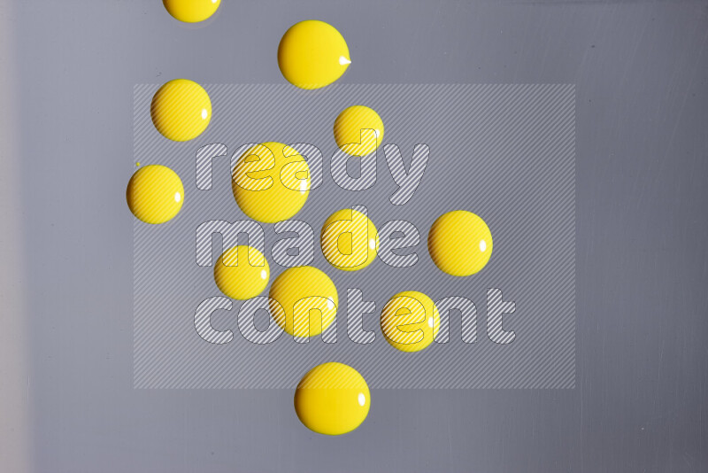 Close-ups of abstract yellow paint droplets on grey background
