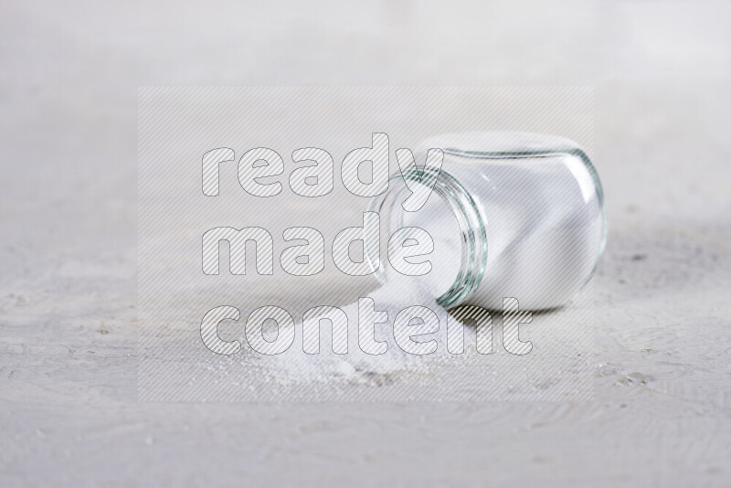 A glass jar full of fine table salt on white background