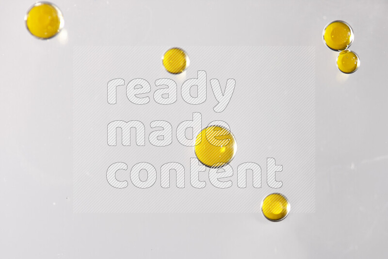 Close-ups of abstract yellow watercolor drops on oil Surface on white background