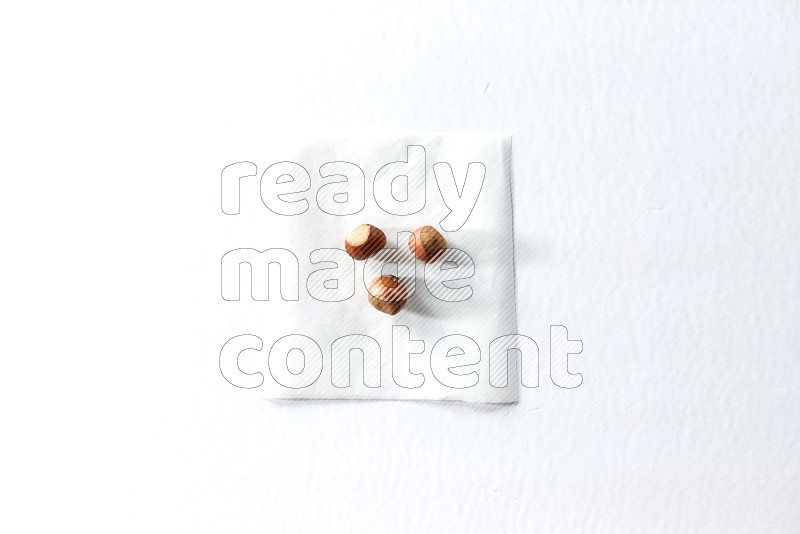 3 hazelnuts on a piece of paper on a white background in different angles