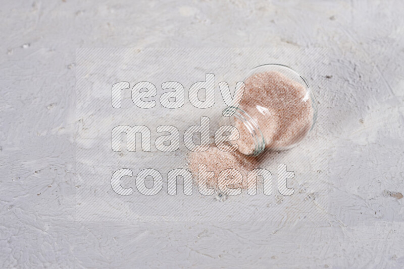 A glass jar full of fine himalayan salt on white background