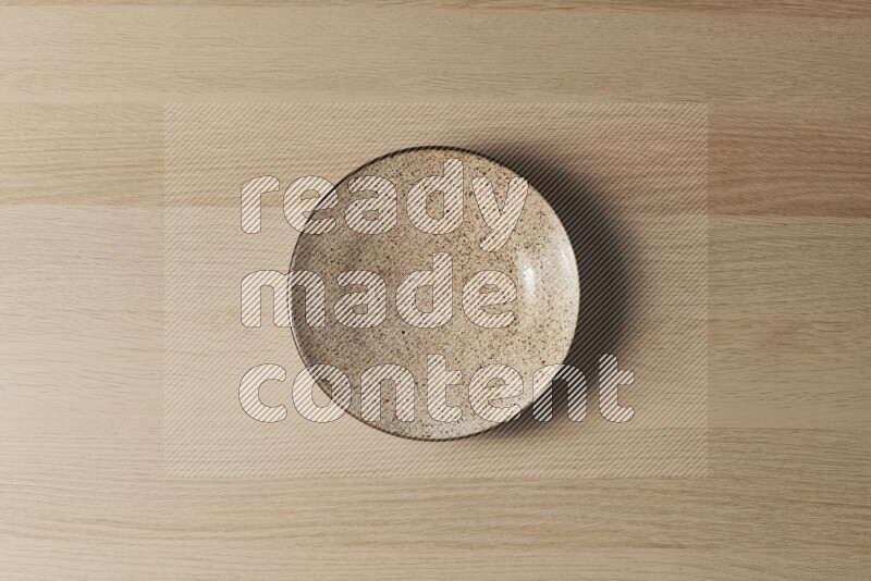 A multicolored pottery plate on light wooden background