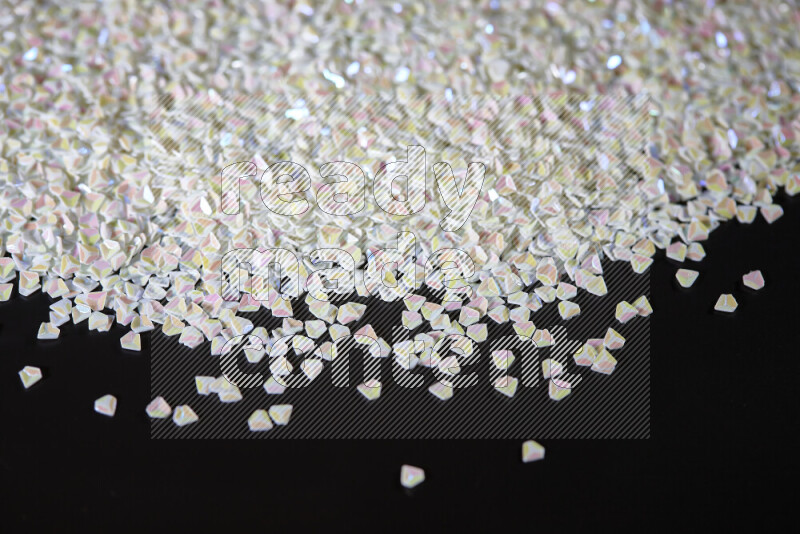 قطع صغيرة بلاستيكية ملونة للزينة متناثرة على خلفية سوداء