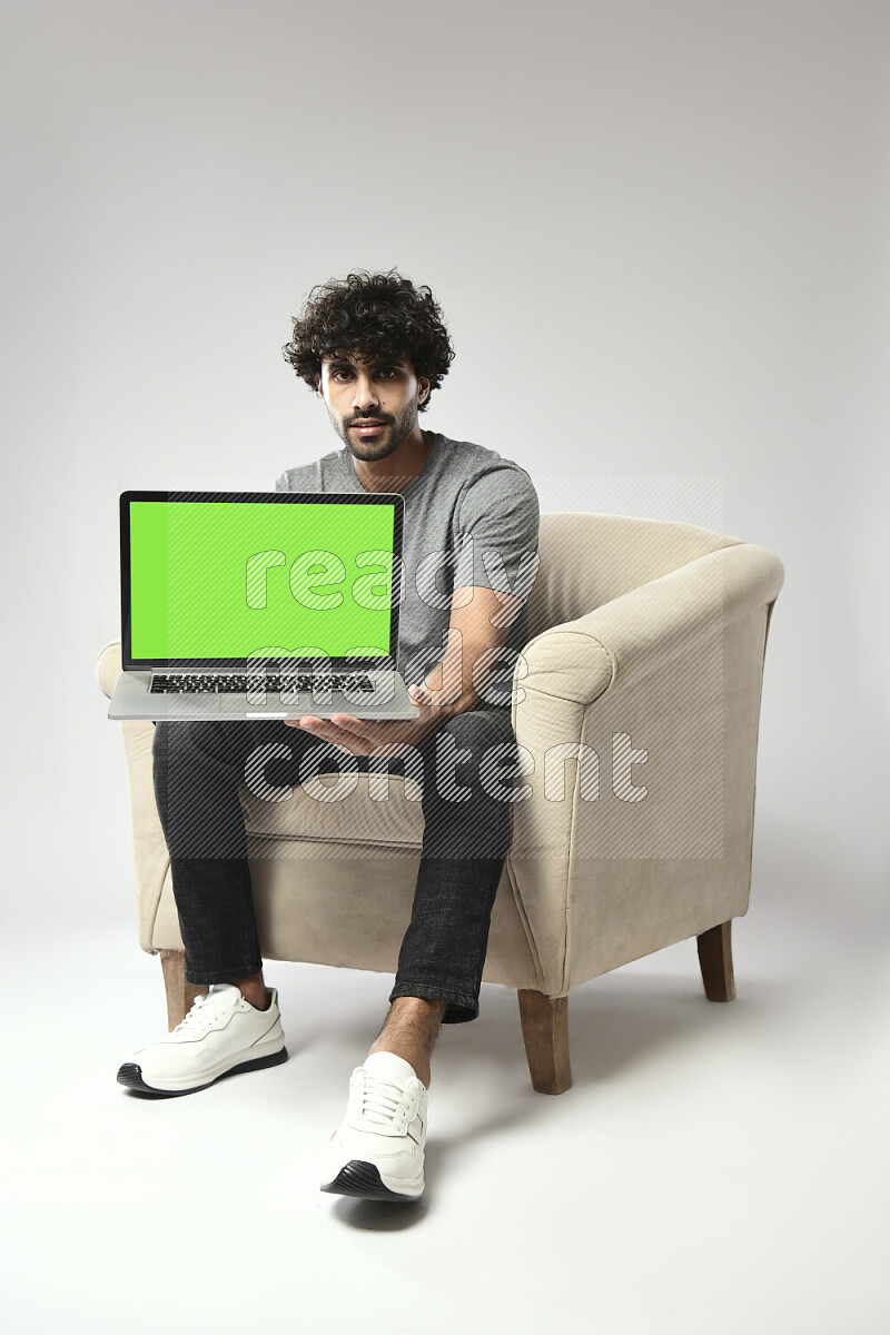 A man wearing casual sitting on a chair showing a laptop screen on white background