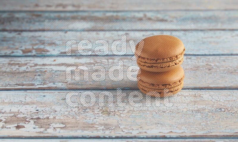 45º Shot of two Brown Maple Taffy macarons on light blue wooden background