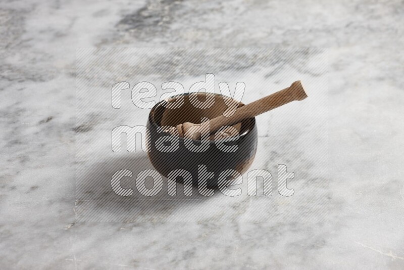 وعاء فخاري متعدد الألوان مع ملعقة عسل خشبية بداخله على خلفية من الرخام الرمادي