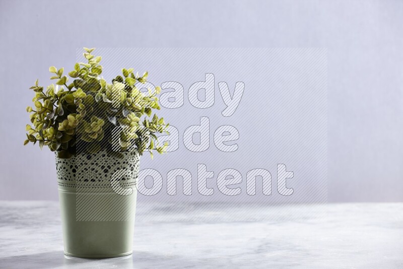 Artificial plant in green decorative pot on grey marble background