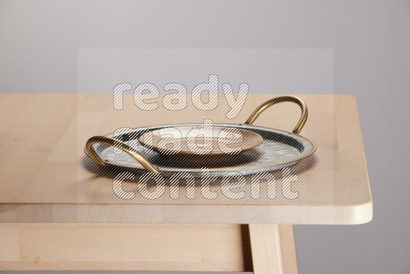 multicolored plate placed on a rounded stainless steel tray with golden handels on the edge of wooden table