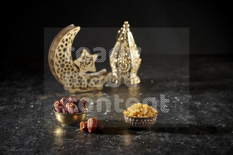 Dates in a metal bowl with raisins beside golden lanterns in a dark setup