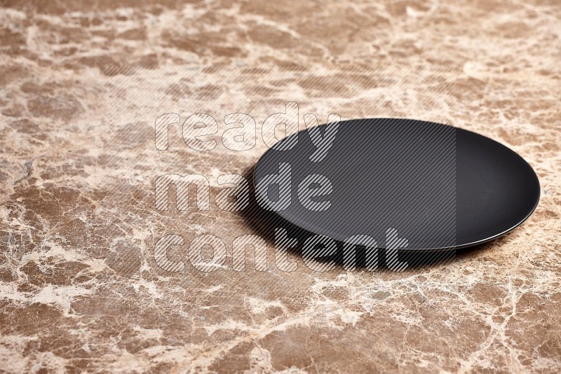 Black Ceramic Circular Plate on Beige Marble Flooring, 45 degrees