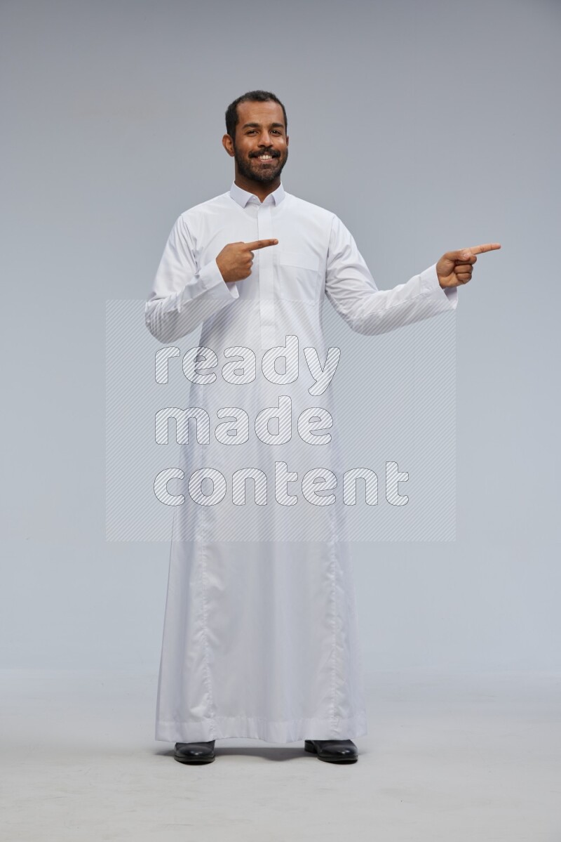 Saudi man Wearing Thob standing interacting with the camera on Gray background
