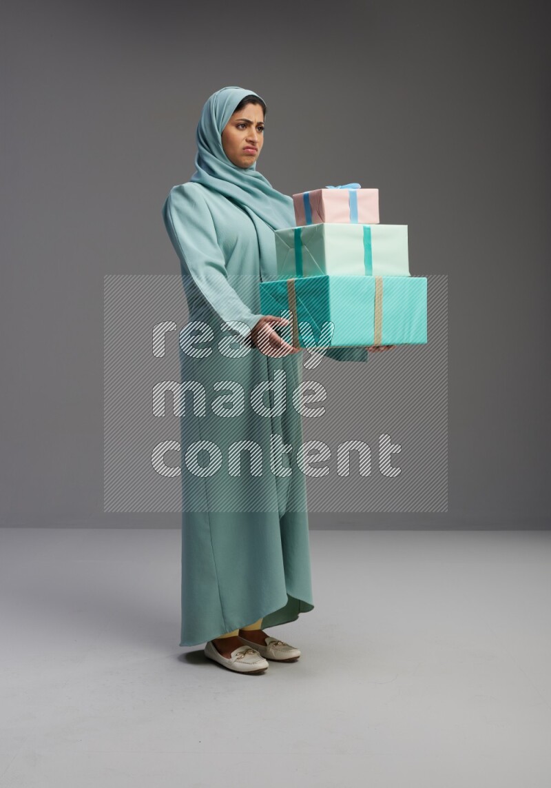 Saudi Woman wearing Abaya standing holding gift box on Gray background