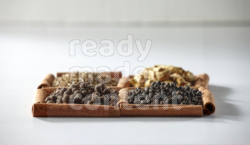 4 squares of cinnamon sticks full of cumin, turmeric fingers, allspice and black pepper on white flooring