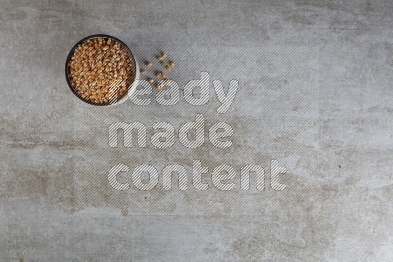 corn kernel in multi-colored pottery bowl on a grey textured countertop