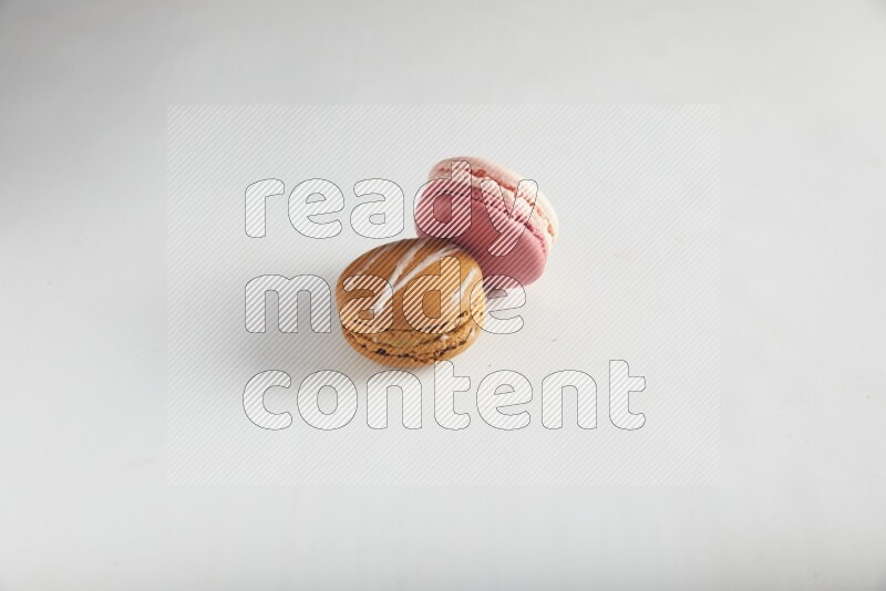 45º Shot of of two assorted Brown Irish Cream, and Pink Litchi Raspberry macarons on white background