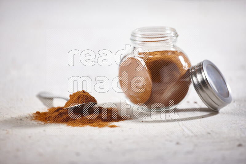 A glass jar full of ground paprika powder on white background