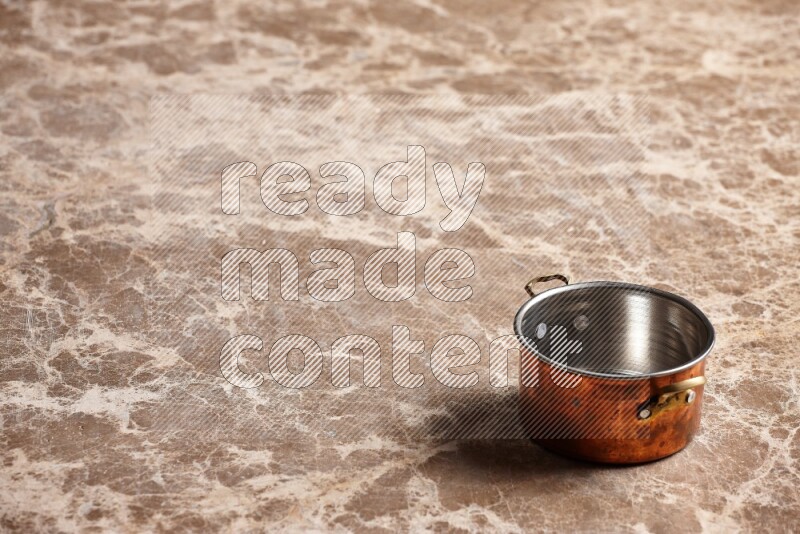 A small copper pot on beige marble background