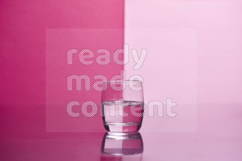 The image features a clear glassware filled with water, set against pink background