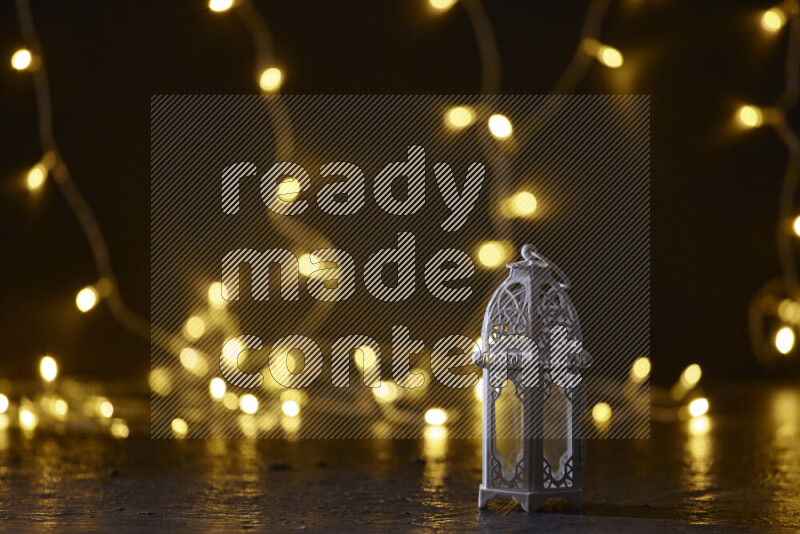 A traditional ramadan lantern surrounded by glowing fairy lights in a dark setup