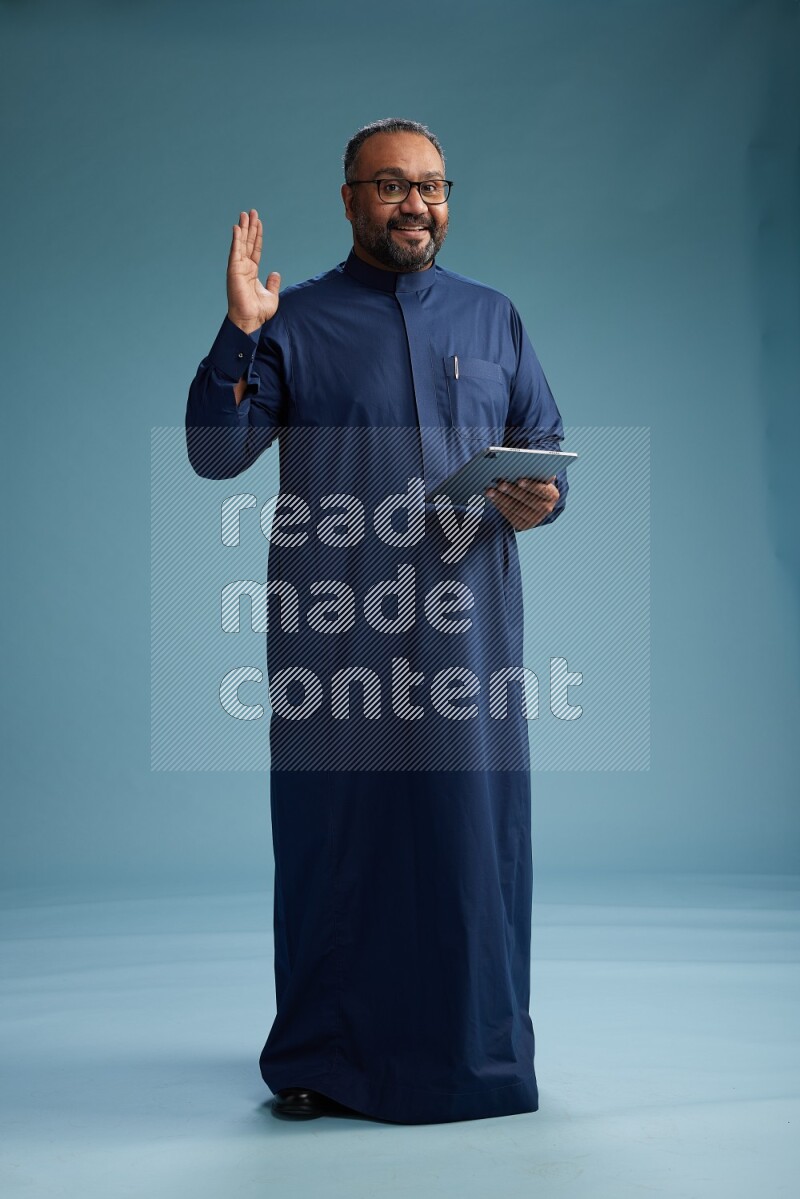 Saudi Man without shimag Standing working on tablet on blue background