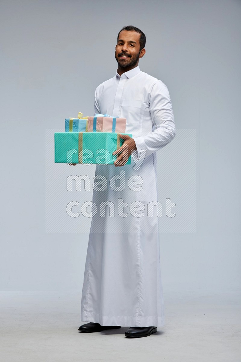 Saudi man Wearing thob standing holding gift box on Gray background