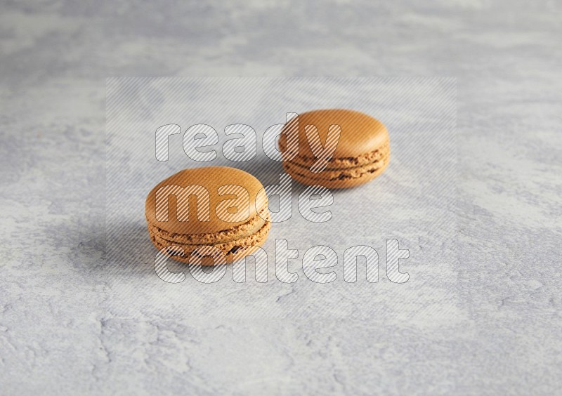 45º Shot of two Brown Maple Taffy macarons  on white  marble background