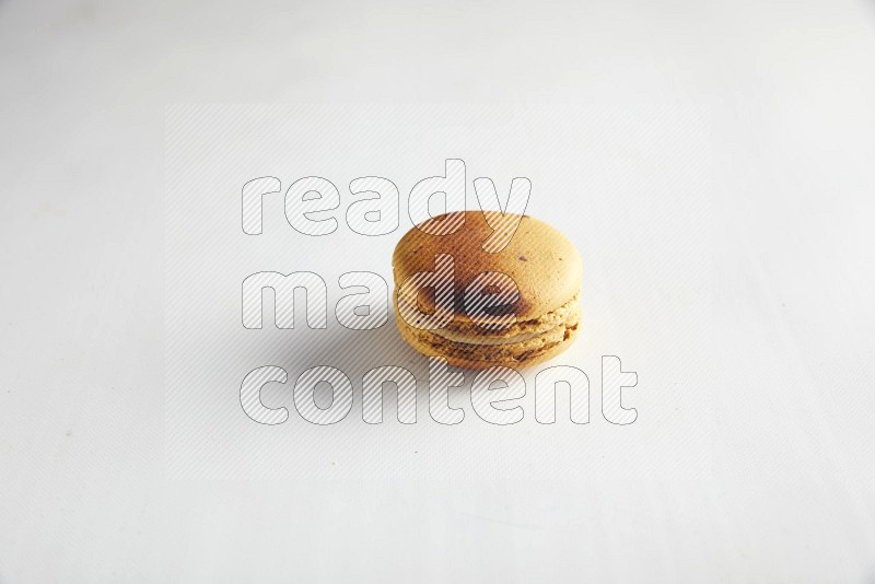 45º Shot of Yellow Crème Brulée macaron on white background